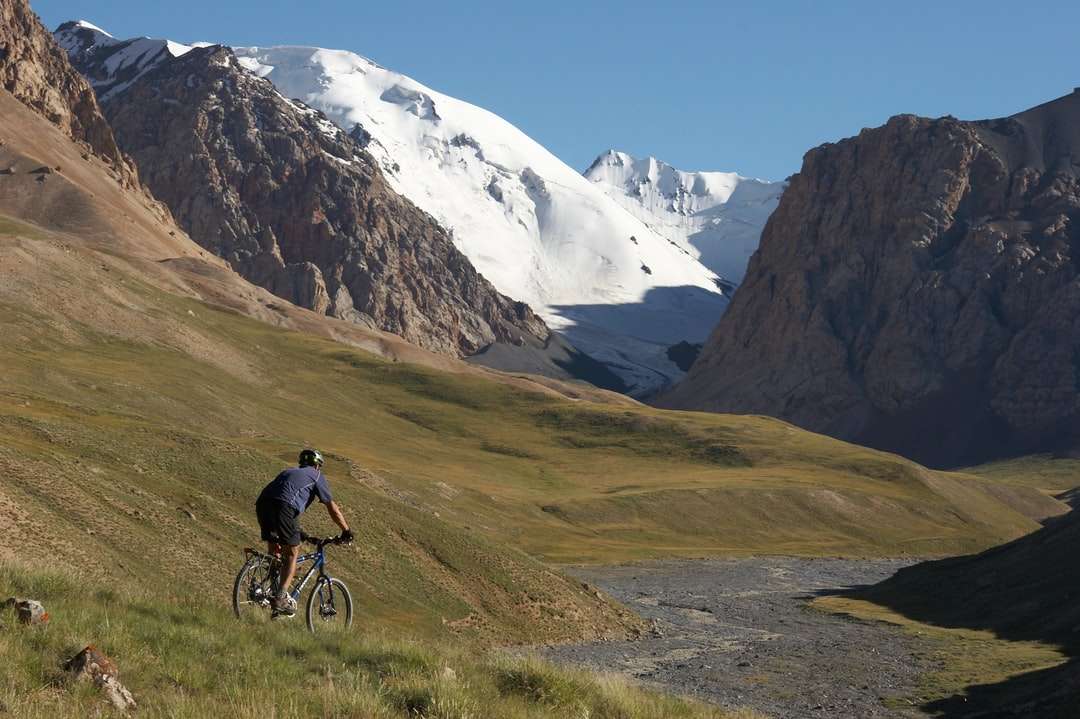 férfi kék kabát, kerékpározás, zöld füves területen kirakós online