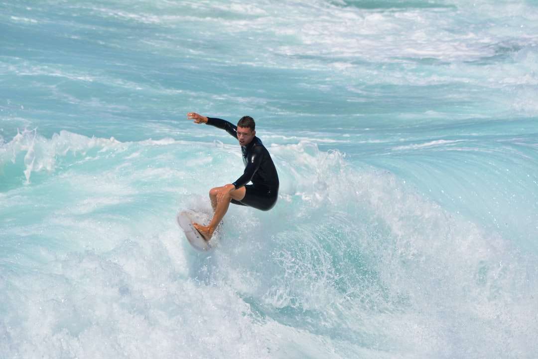 nő fekete wetsuit szörfözés a tenger hullámai napközben kirakós online