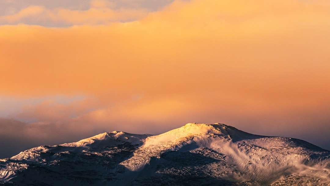 montanha coberta de neve sob céu laranja puzzle online