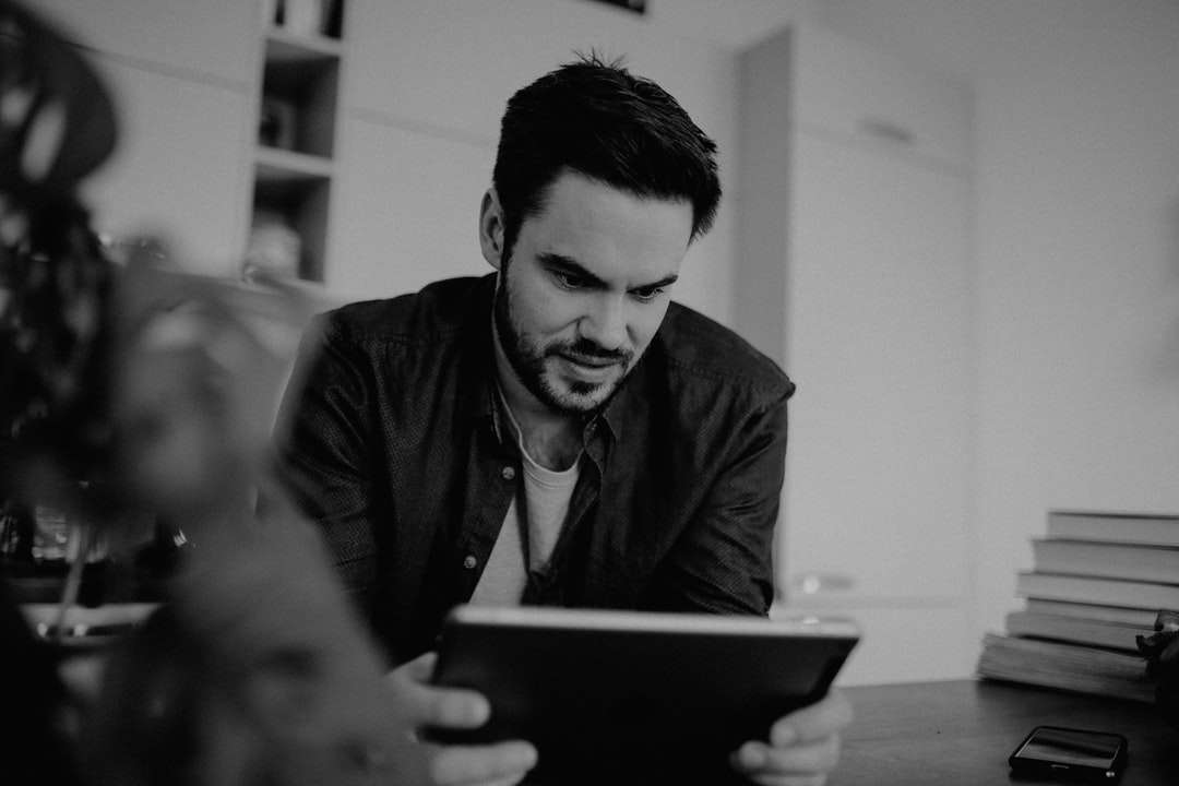 Mann in der schwarzen Anzugjacke, die weißen Tablet-Computer hält Puzzlespiel online