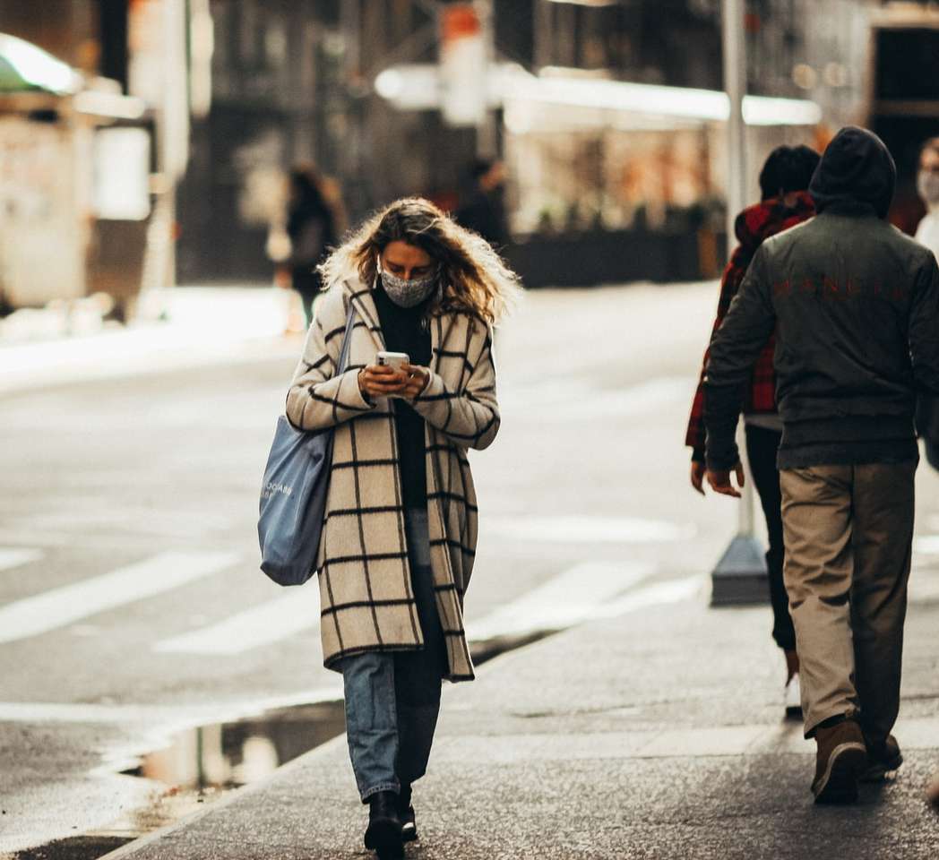 Frau im weißen und schwarzen Mantel, der auf Bürgersteig geht Puzzlespiel online