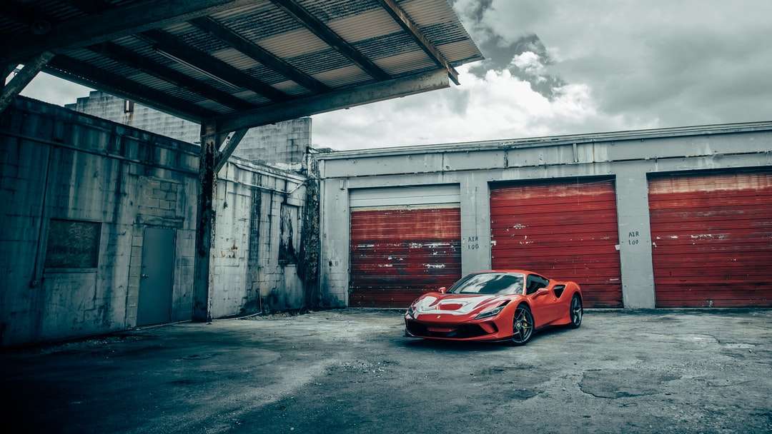 Porsche 911 roșu și alb parcat lângă clădirea de beton gri puzzle online