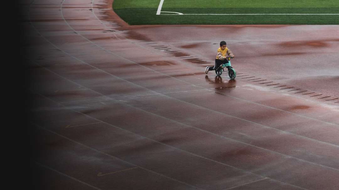 menino de camisa azul andando de bicicleta no campo de atletismo puzzle online