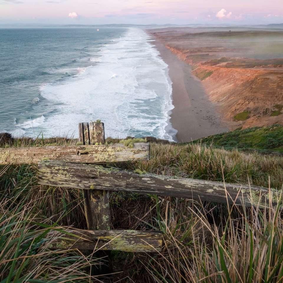 gard de lemn maro pe malul mării în timpul zilei puzzle online