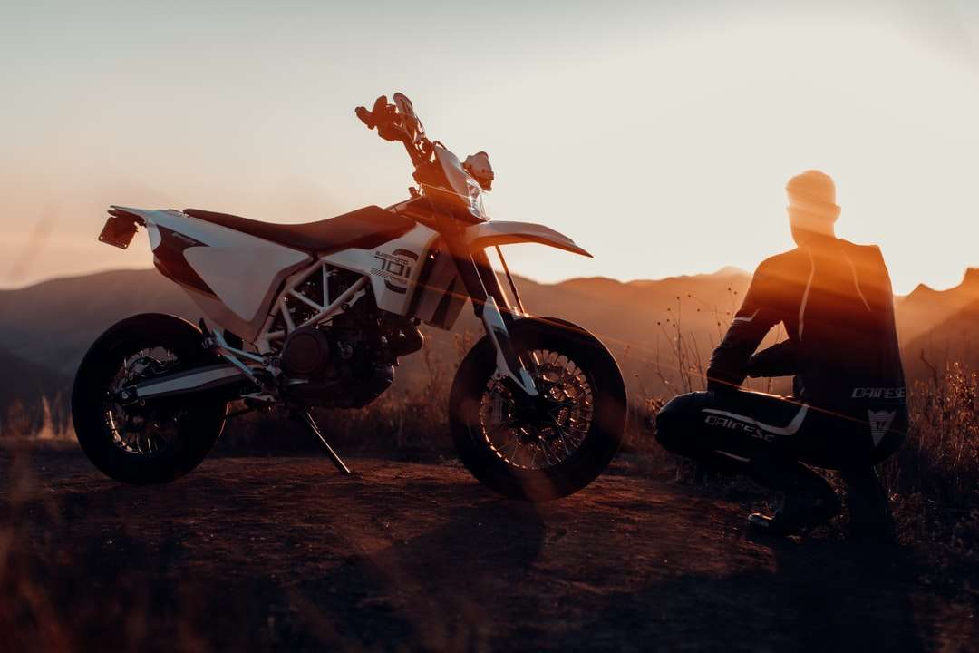 man i svart jacka sitter på motorcykel under solnedgången Pussel online
