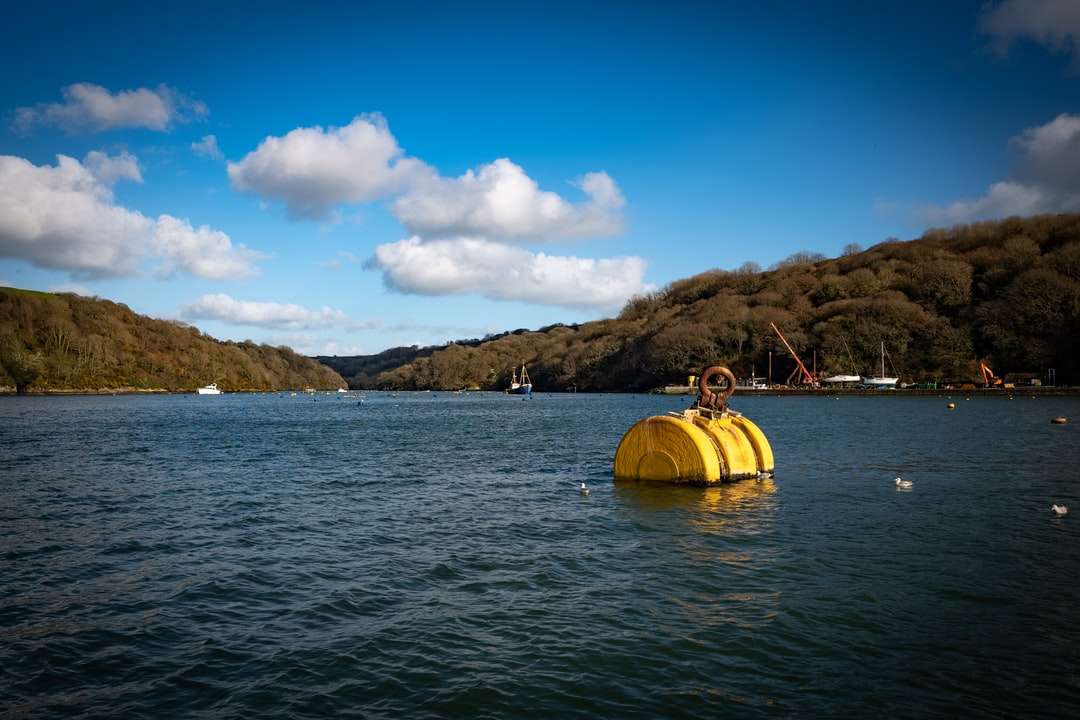 kayak jaune sur la mer près de la montagne sous le ciel bleu puzzle en ligne