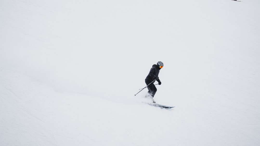 Hombre con chaqueta negra y pantalón negro montando cuchillas de esquí rompecabezas en línea