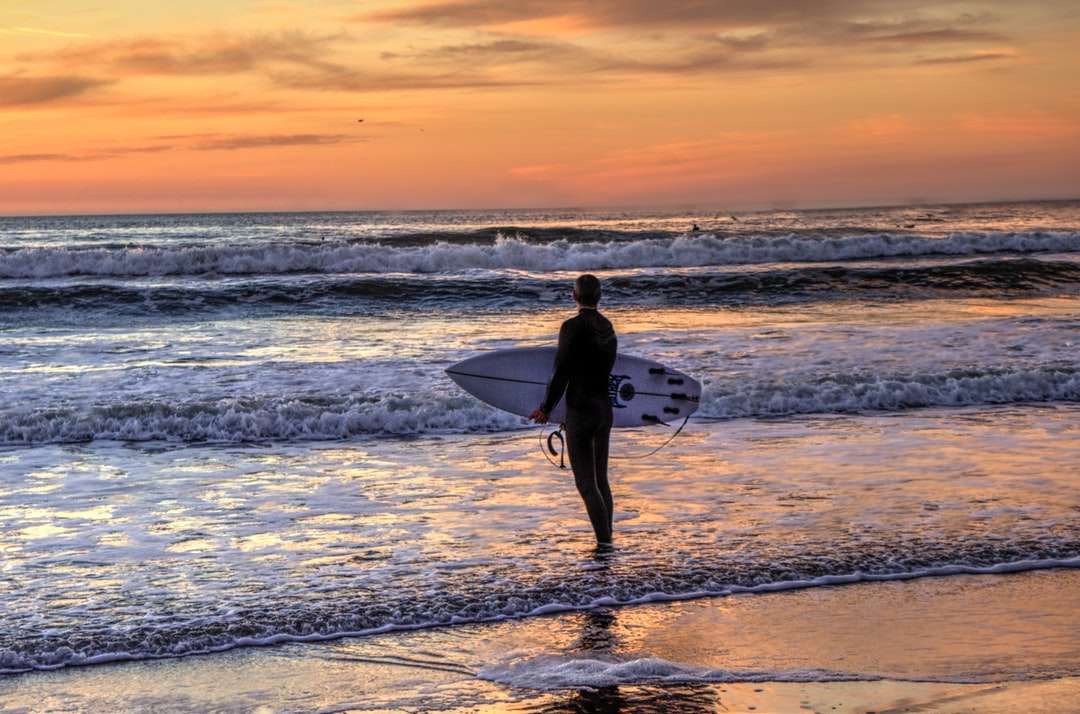 om în costum negru care deține o placă de surf albă puzzle online