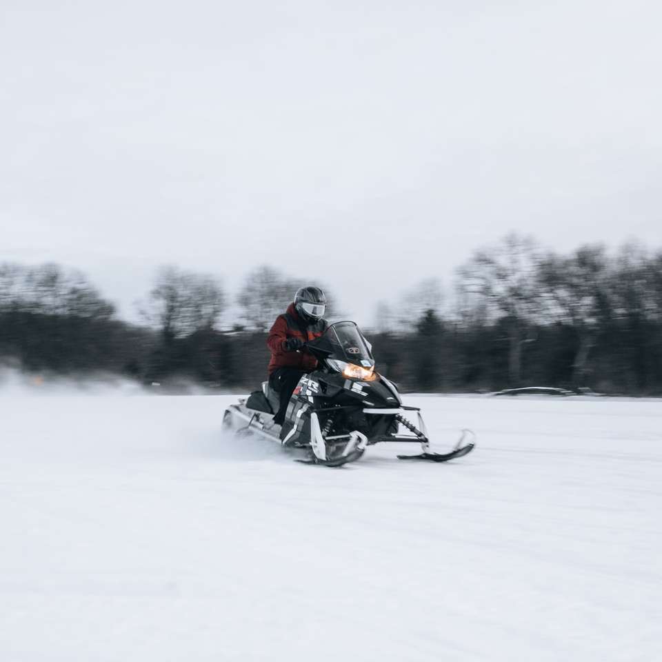 Mann, der auf schwarzem Motorrad auf schneebedecktem Feld reitet Puzzlespiel online
