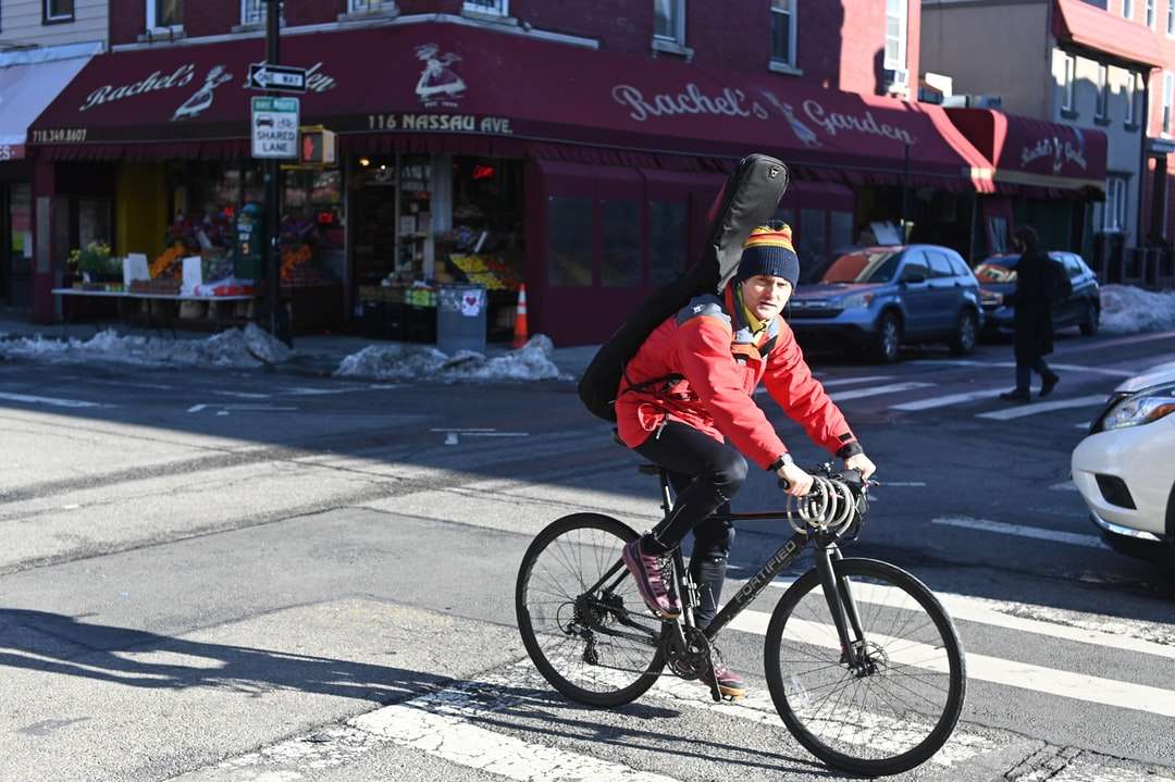 bărbat în jachetă roșie călare pe bicicletă în timpul zilei jigsaw puzzle online