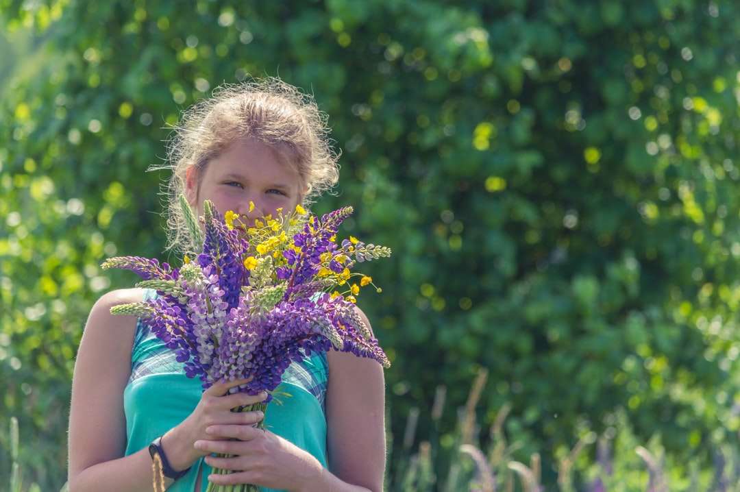 dívka v modrých šatech bez rukávů drží fialový květ skládačky online
