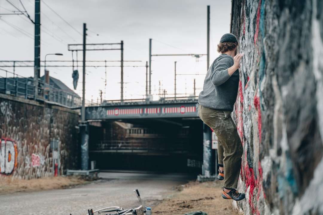 bărbat în jachetă gri și pantaloni gri care dețin skateboard negru puzzle online