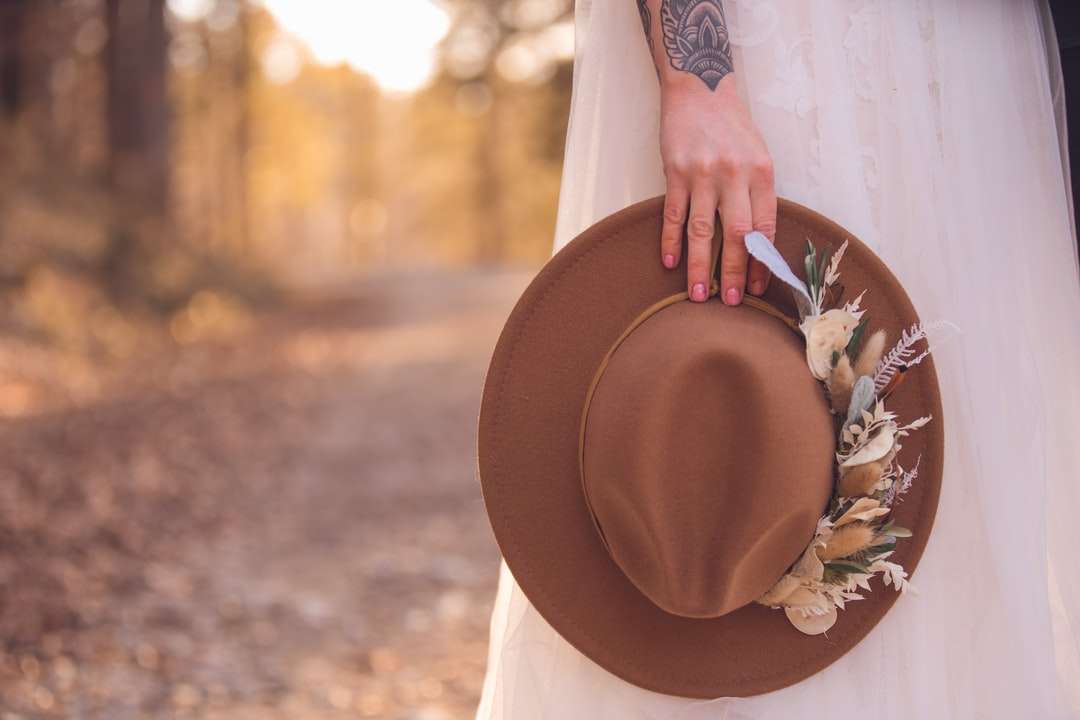 femme en chemise à manches longues blanche tenant un chapeau marron puzzle en ligne