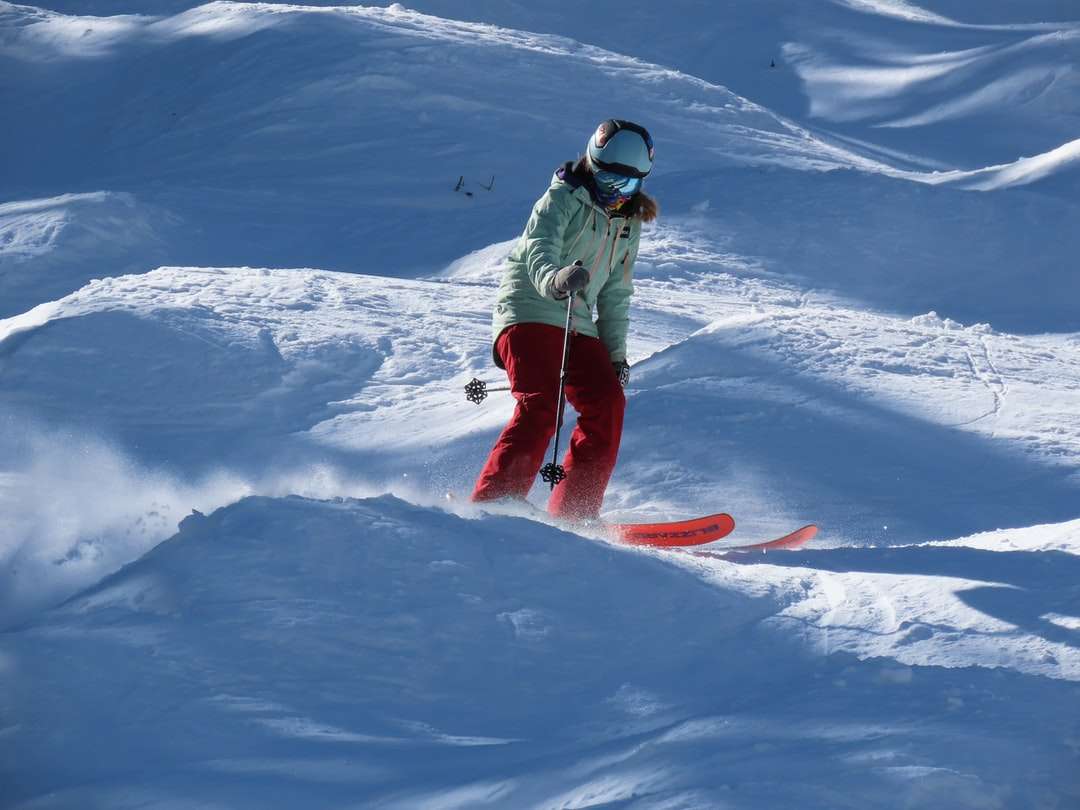 om în sacou verde și pantaloni albaștri călare pe snowboard roșu puzzle online