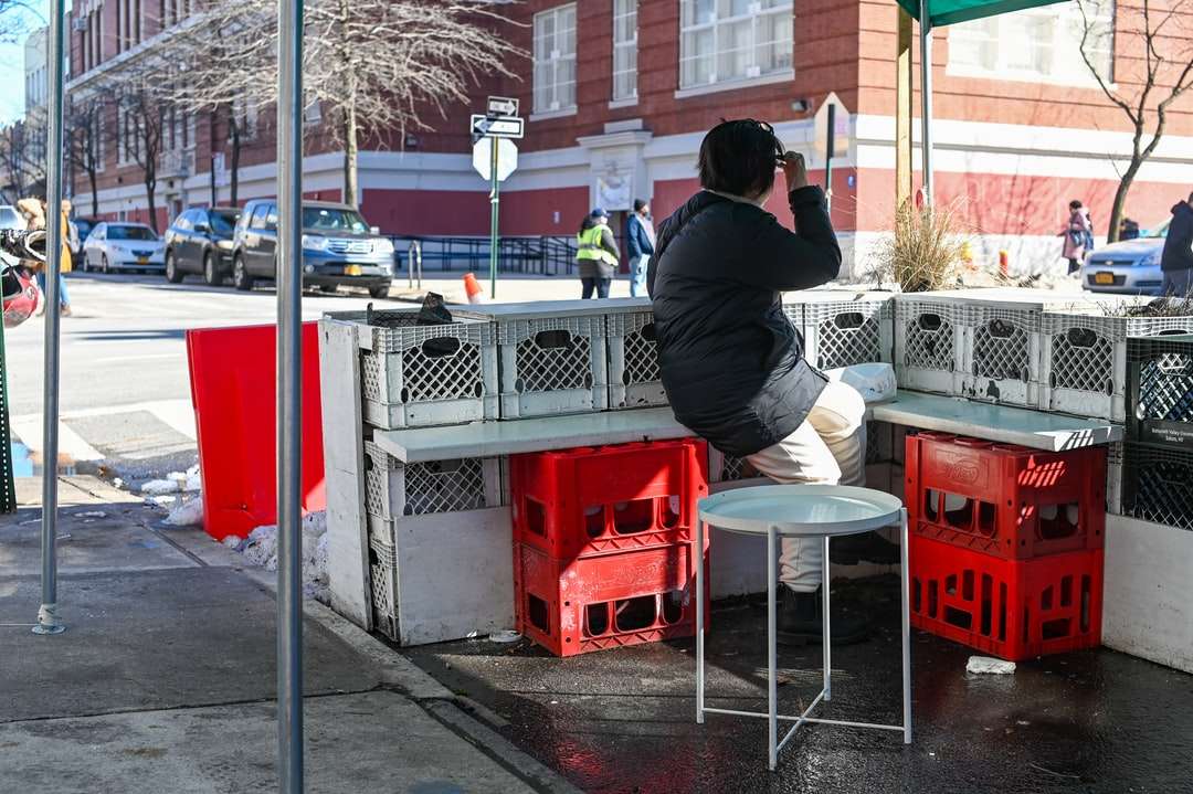 homem de jaqueta preta sentado em um assento de plástico vermelho puzzle online