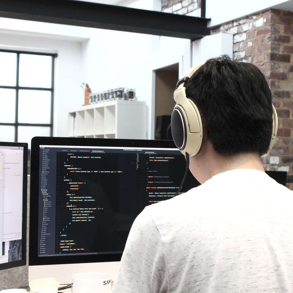 мъж, който носи слушалки, докато използва компютър онлайн пъзел