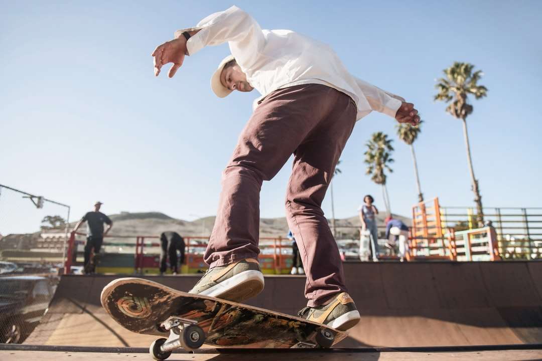 bărbat în cămașă de rochie albă și pantaloni maro skateboard puzzle online