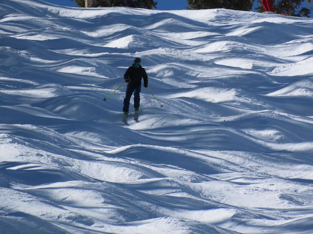 Persona en chaqueta negra caminando sobre suelo cubierto de nieve rompecabezas en línea