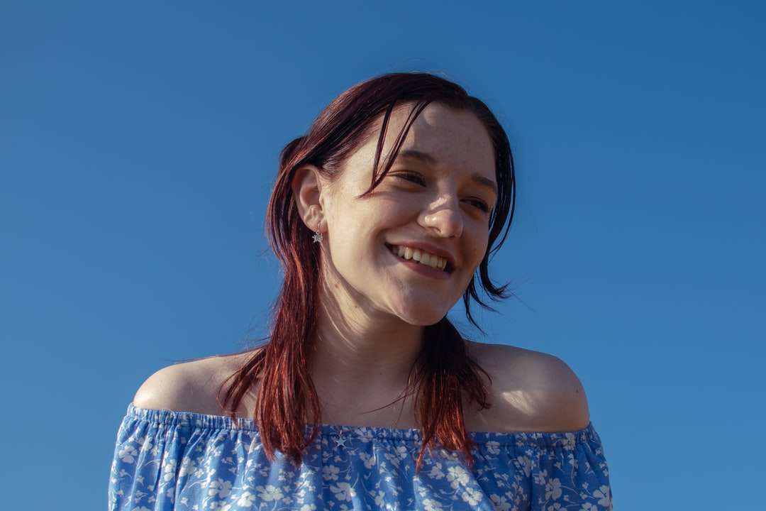 glimlachende vrouw in blauwe en witte bloemenbuisjurk legpuzzel online