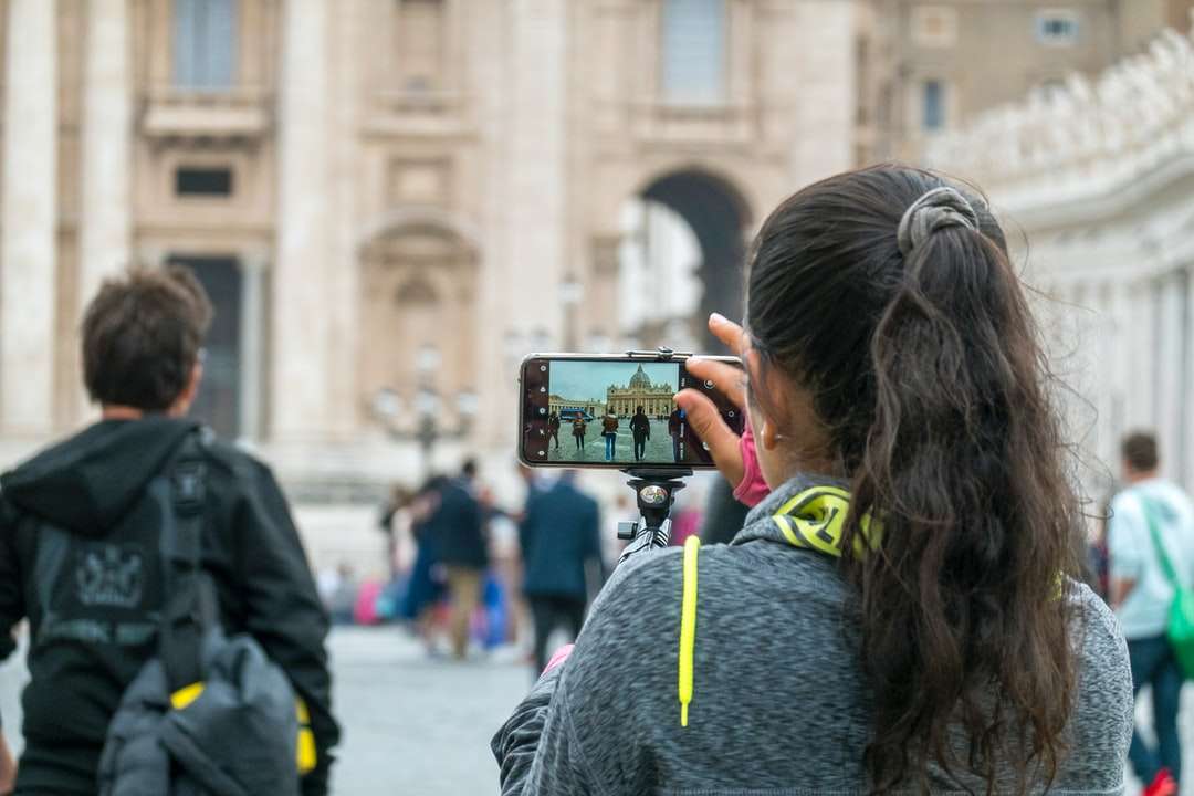 žena v šedá mikina drží černý smartphone online puzzle