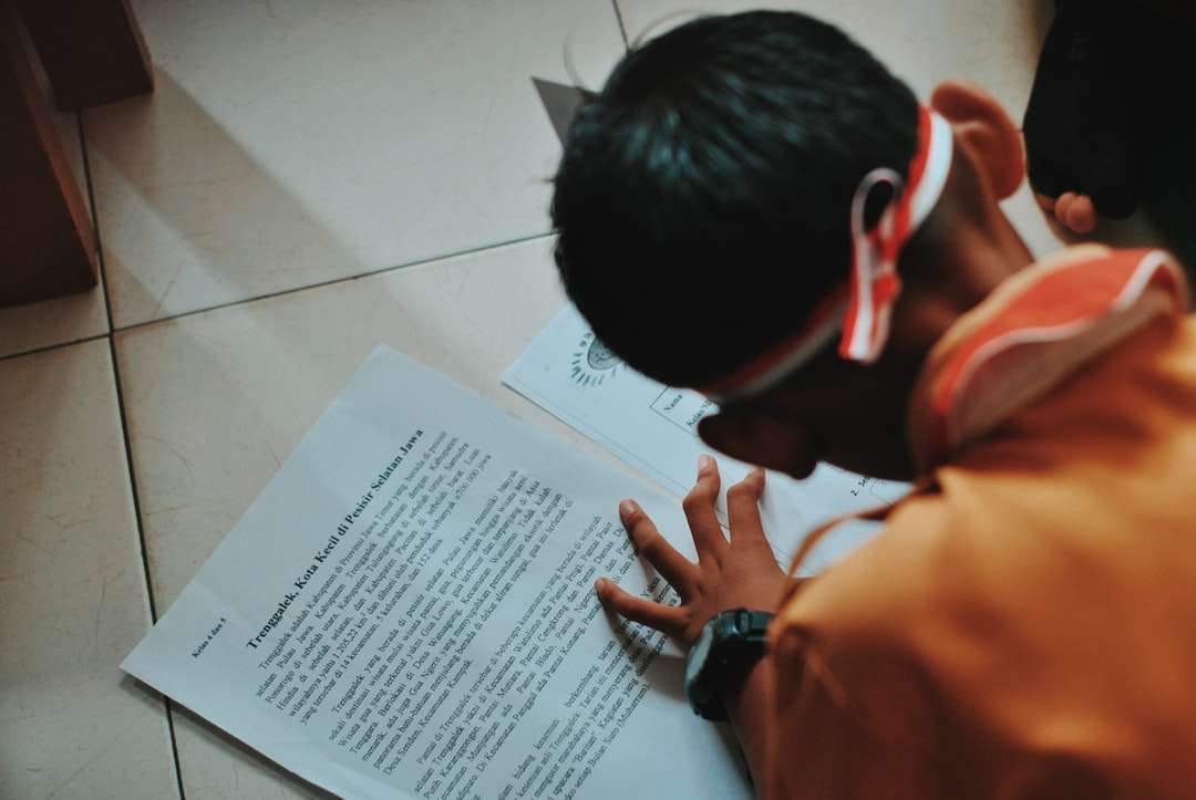 мъж в оранжева риза, пишеща на бяла хартия онлайн пъзел