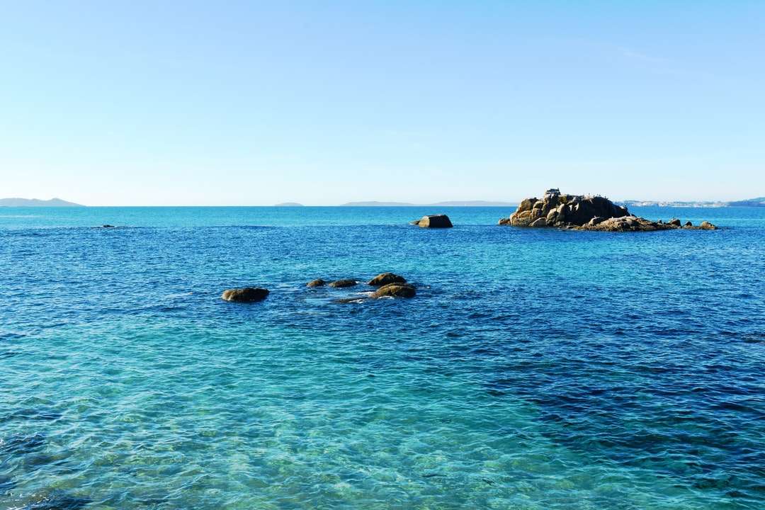skalnaté pobřeží pod modrou oblohou během dne online puzzle