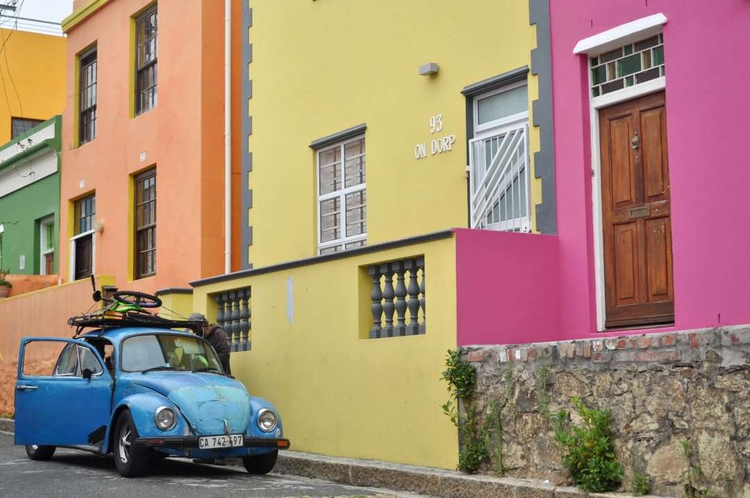 mașină albastră parcată lângă clădirea din beton galben puzzle online