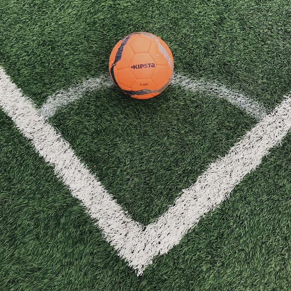 оранжева футболна топка на поле със зелена трева онлайн пъзел