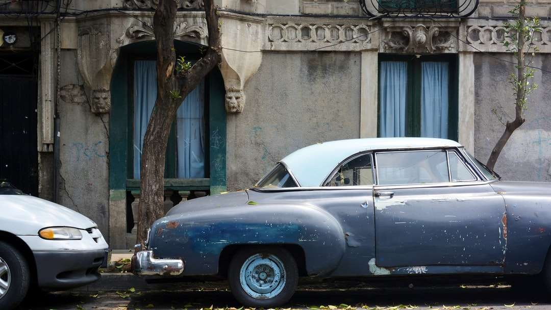 blaues klassisches Auto, das tagsüber neben grünem Baum geparkt wird Puzzlespiel online