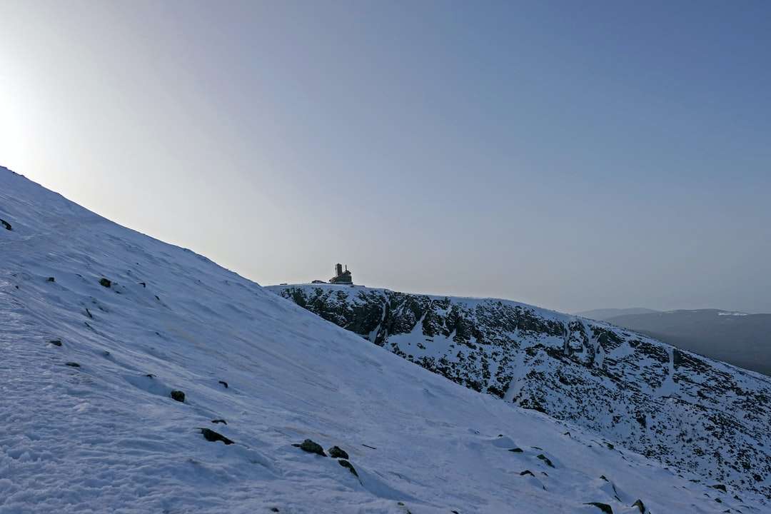 pessoa em pé na montanha coberta de neve durante o dia quebra-cabeças online