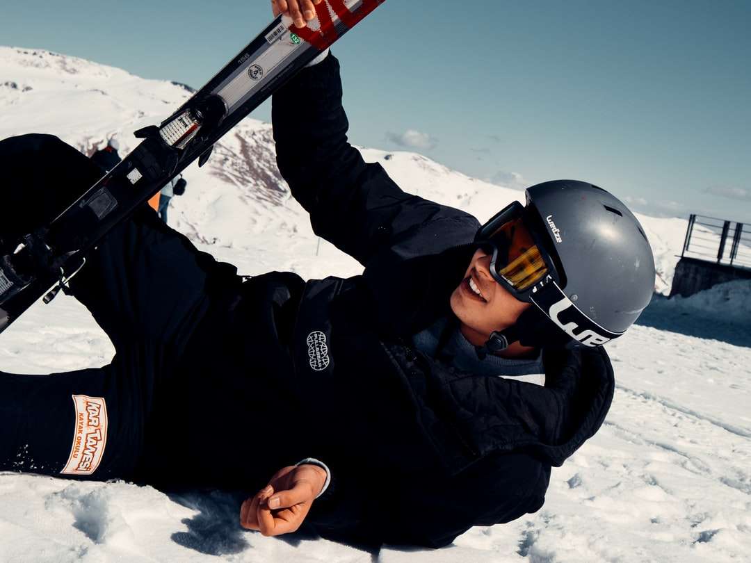 homem de jaqueta preta segurando uma prancha de esqui na neve vermelha e preta quebra-cabeças online