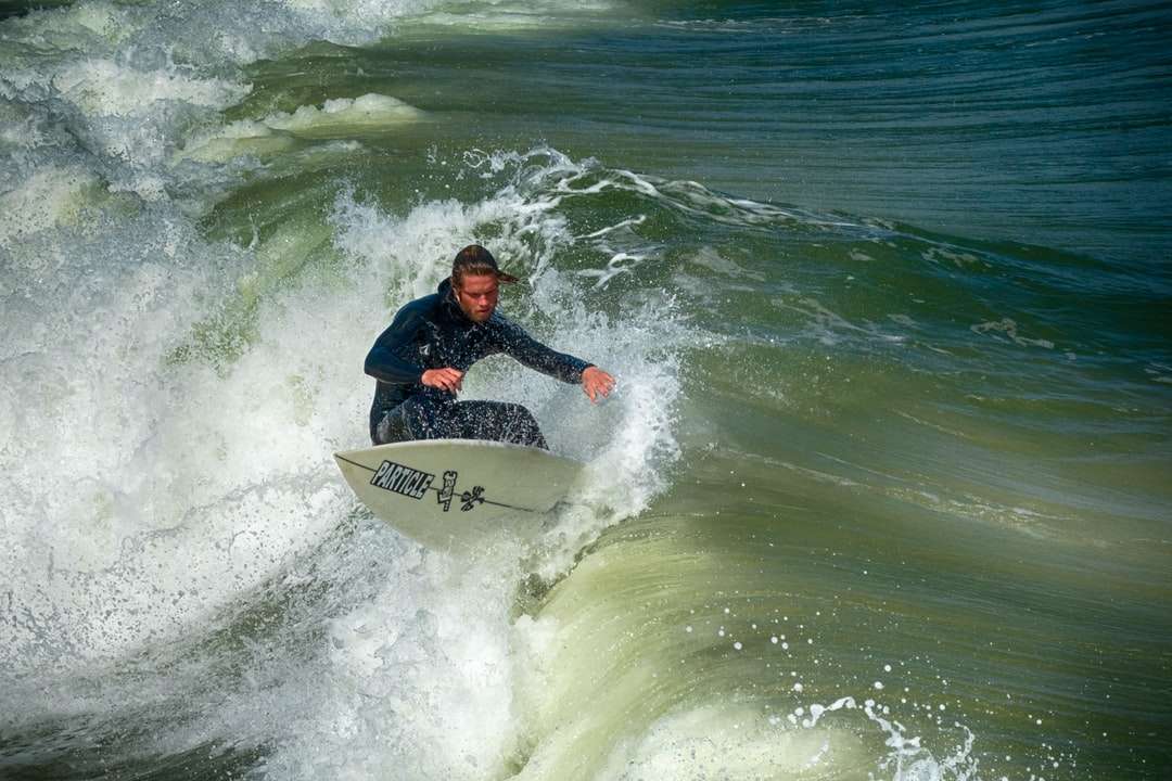 Hombre de chaqueta negra y roja surfeando en las olas del mar rompecabezas en línea