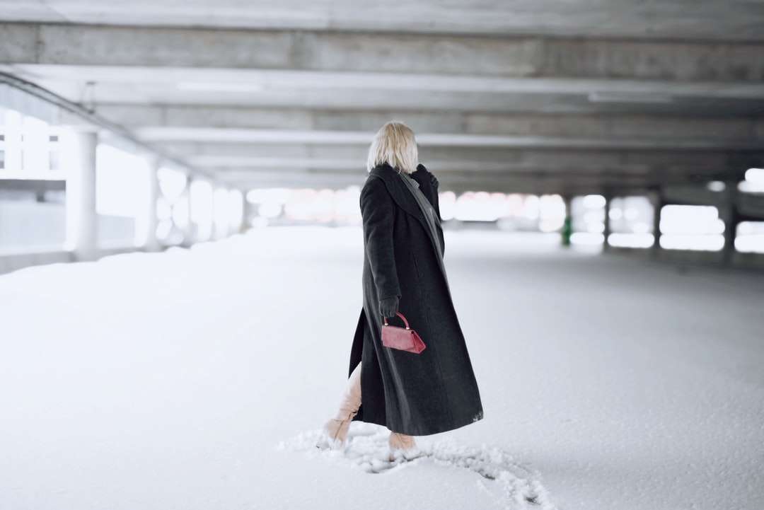Mujer de abrigo negro de pie sobre un suelo cubierto de nieve rompecabezas en línea