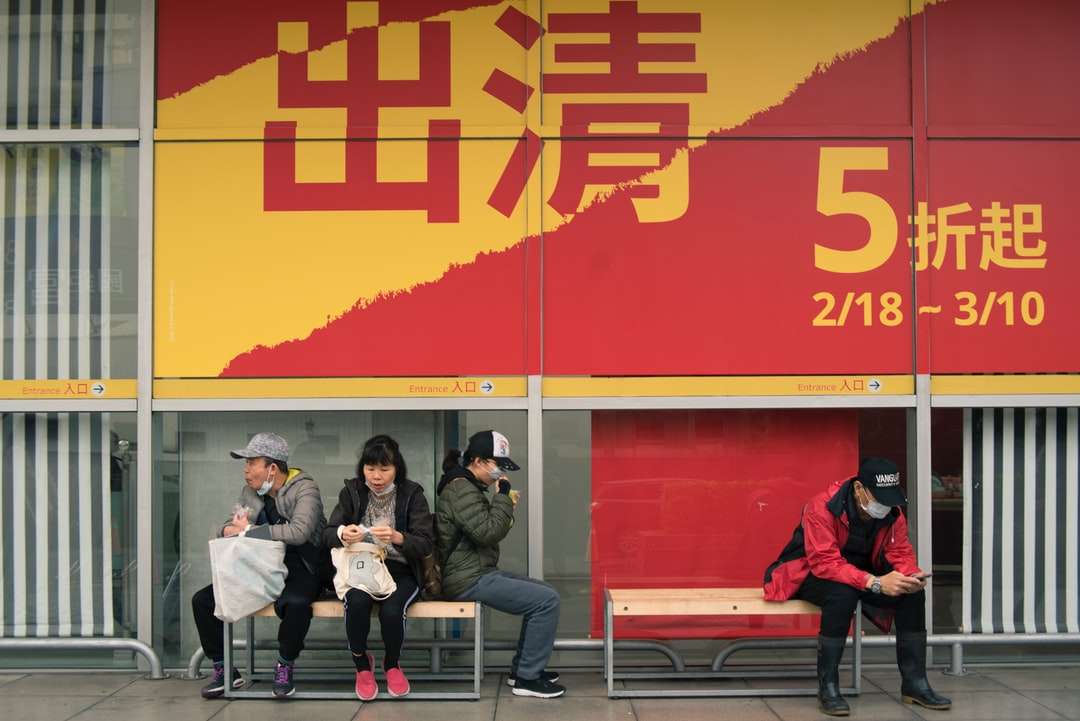 emberek ülnek a padon, piros fal közelében online puzzle
