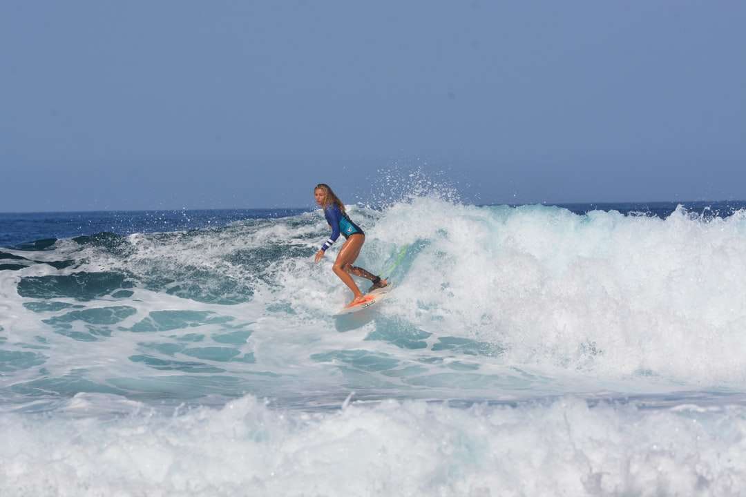 Mujer en bikini azul y blanco surfeando en las olas del mar rompecabezas en línea