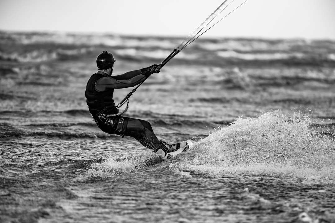 Hombre con chaqueta negra y pantalón negro jugando windsurf rompecabezas en línea
