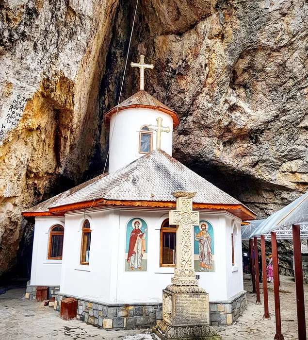 Kirche vor Felsenhöhle in Rumänien Online-Puzzle