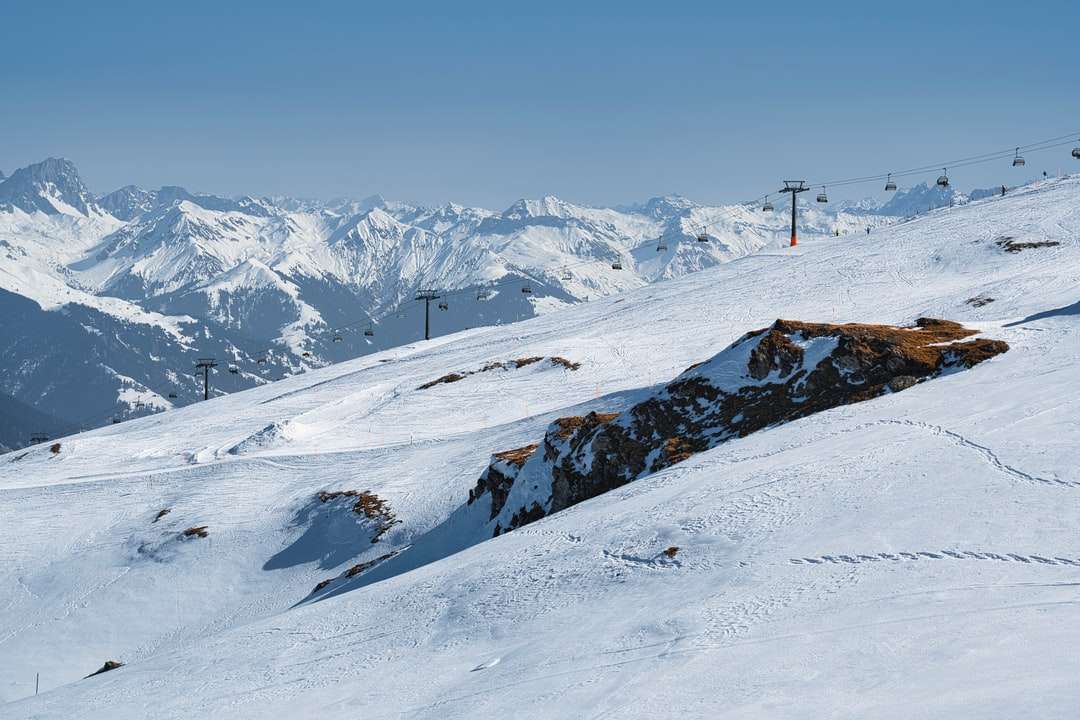 човек в черно яке, стоящ на заснежена планина онлайн пъзел