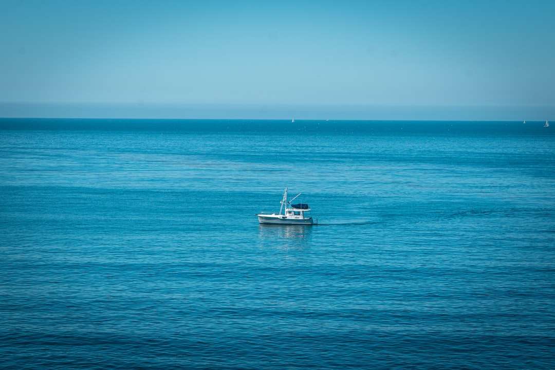 белая лодка на синем море под голубым небом в дневное время пазл онлайн