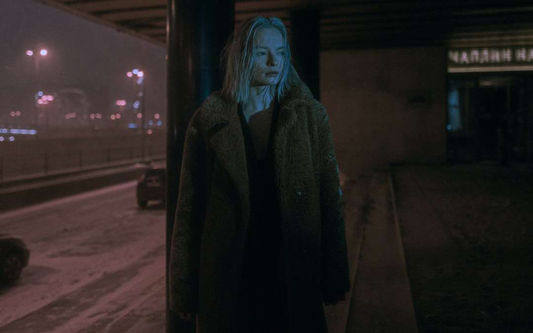 夜の間に歩道に立っている黒いコートの女性 オンラインパズル