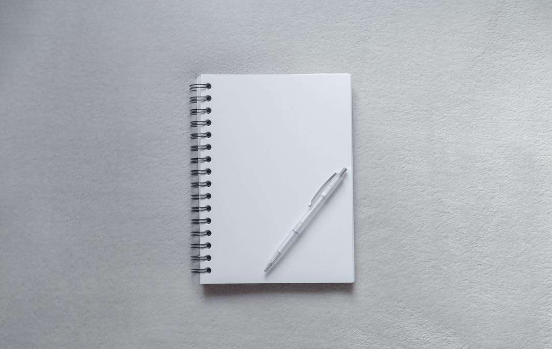 vit anteckningsbok med penna på toppen Pussel online