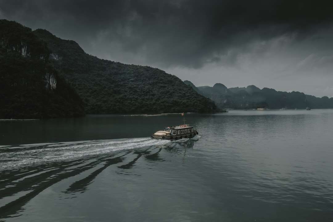 коричневий човен на водоймі біля гори в денний час онлайн пазл