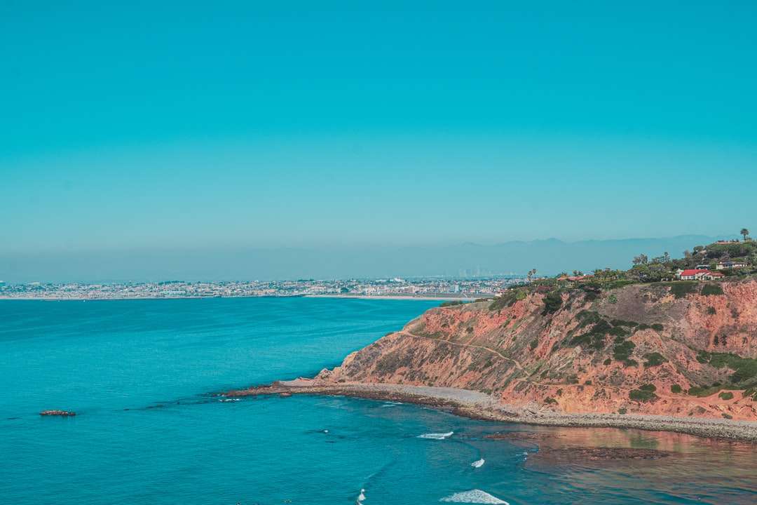 зелена и кафява планина до синьо море под синьо небе онлайн пъзел