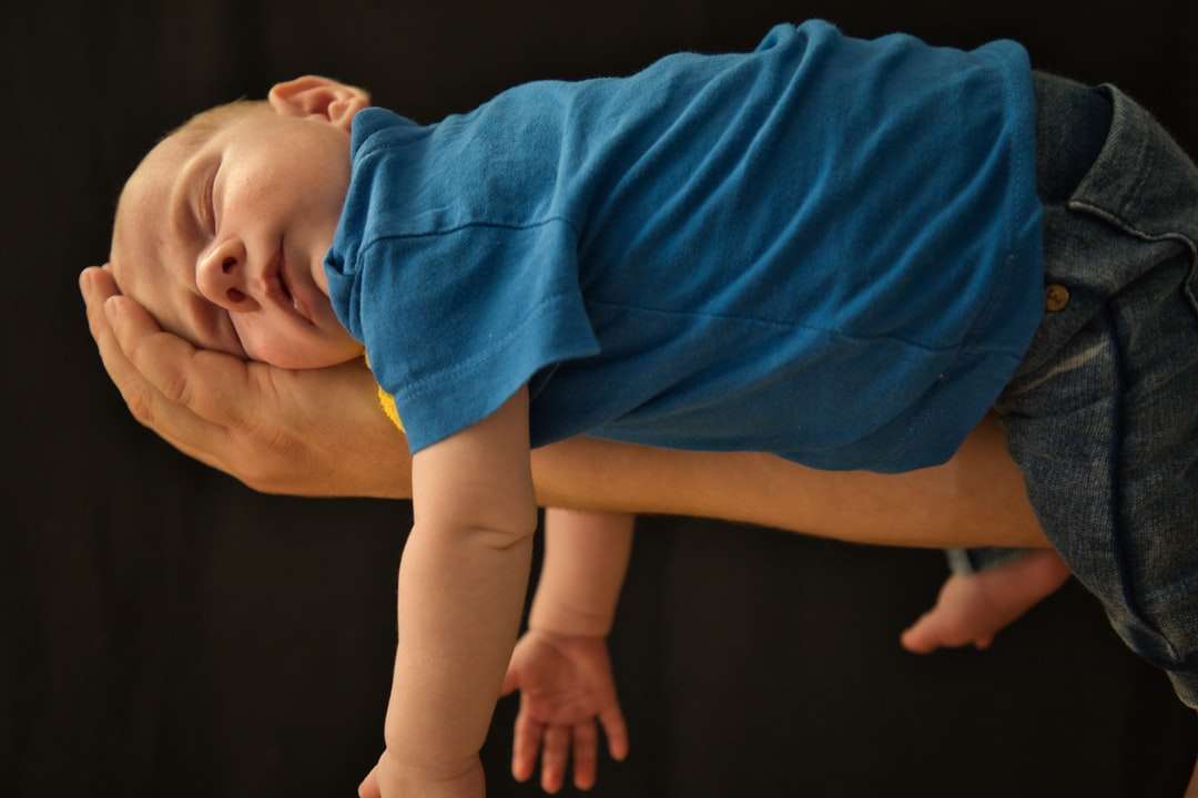 Bébé en chemise bleue allongé sur un plancher en bois marron puzzle en ligne