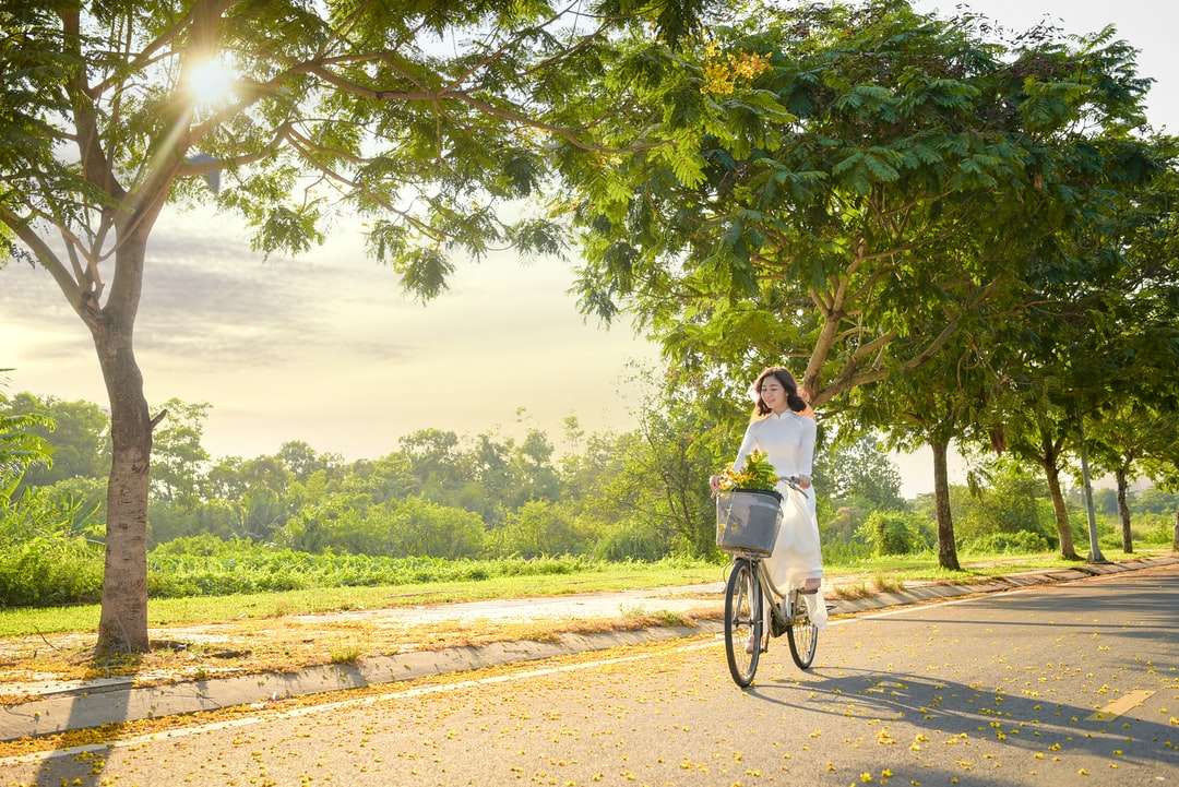 жена в бяла риза, каране на велосипед по кафяв черен път онлайн пъзел