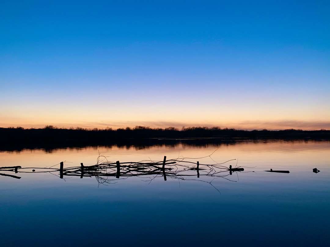 staccionata in legno marrone sul lago durante il tramonto puzzle online