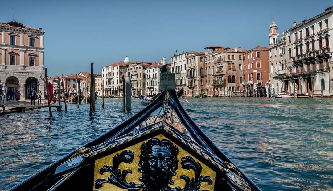 Boot auf dem Wasser in der Nähe von Gebäuden während des Tages Puzzlespiel online
