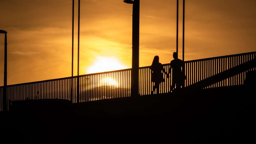 силуэт людей, стоящих на мосту во время заката онлайн-пазл