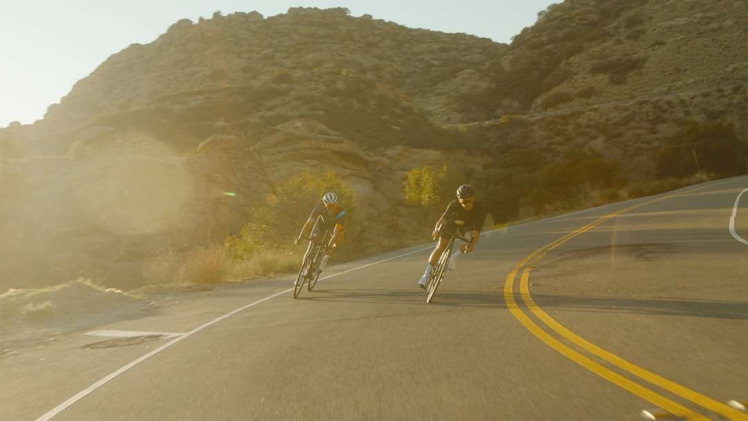 man in white shirt and black shorts riding bicycle on road online puzzle