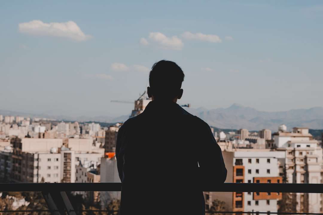 άντρας σε μαύρο σακάκι στέκεται πάνω από το κτίριο online παζλ